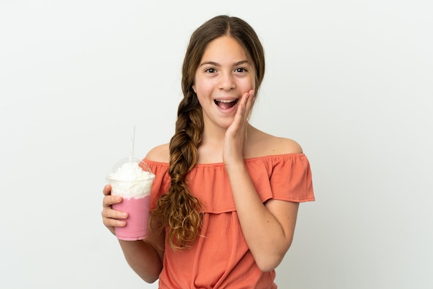 Little caucasian girl with strawberry milkshake isolated on white background with surprise and shocked facial expression