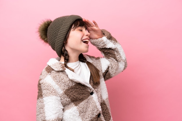 Little caucasian girl with winter jacket isolated on pink background has realized something and intending the solution