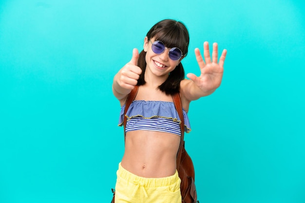 Little caucasian kid going to the beach isolated on blue\
background counting six with fingers