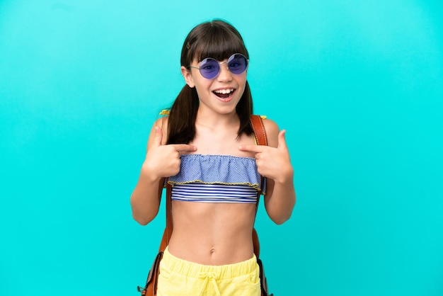 Little caucasian kid going to the beach isolated on blue background with surprise facial expression