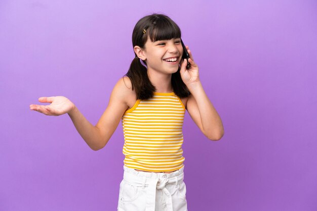 Little caucasian kid isolated on purple background keeping a conversation with the mobile phone with someone