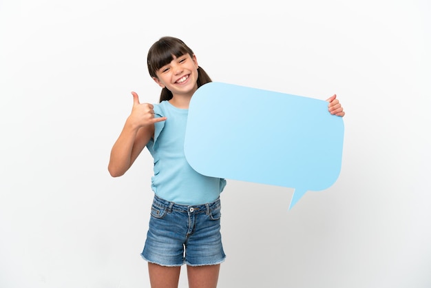 Little caucasian kid isolated on white background holding an empty speech bubble and doing phone gesture