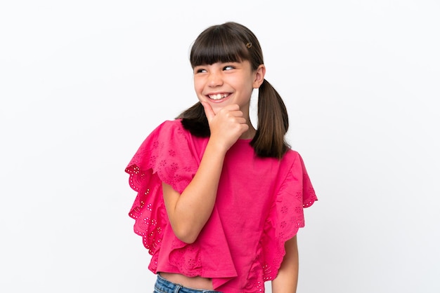 Little caucasian kid isolated on white background looking to the side and smiling