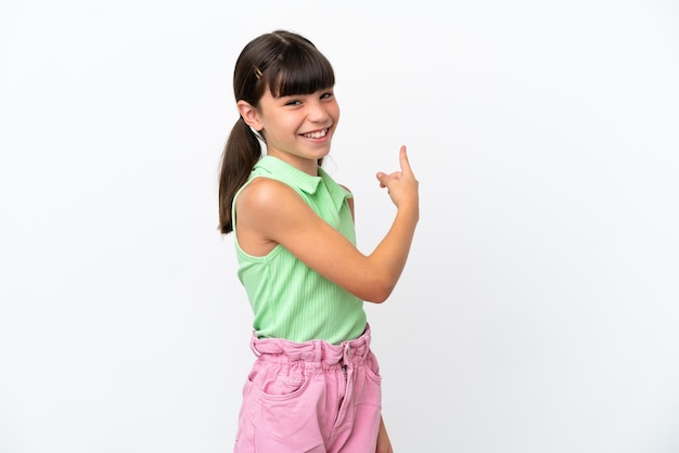 Little caucasian kid isolated on white background pointing back