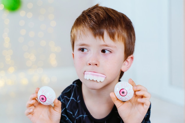 Little caucasian kid playing with Halloween trick or treat candy