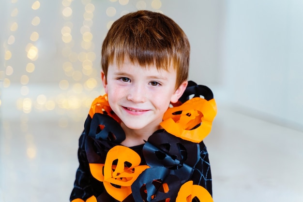 Little caucasian kid playing with trick or treat candy collected at Halloweens costume party