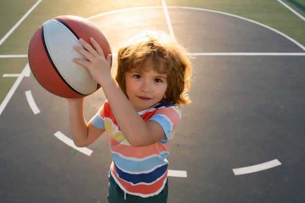 Little caucasian sports kid playing basketball holding ball with happy face Portrait of sporty funny child