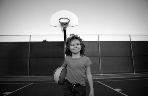 Photo little caucasian sports kid playing basketball holding ball with happy face