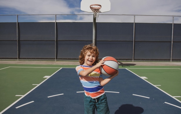 Little caucasian sports kid playing basketball holding ball with happy face