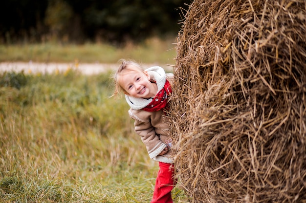 A little cheerful girl next to a haystack