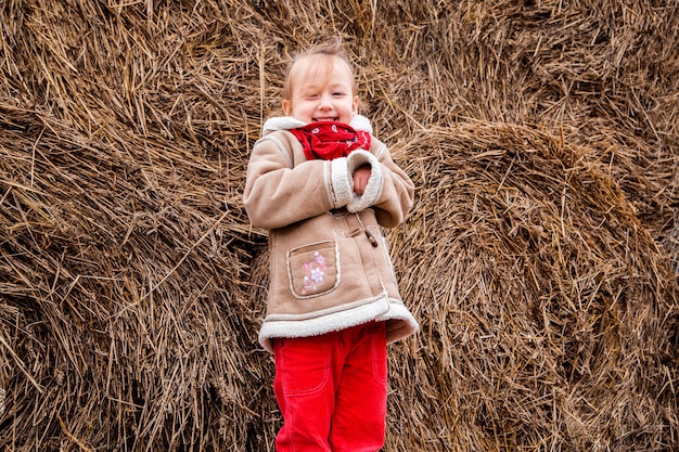 A little cheerful girl next to a haystack