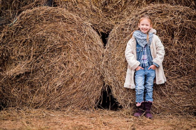 A little cheerful girl next to a haystack