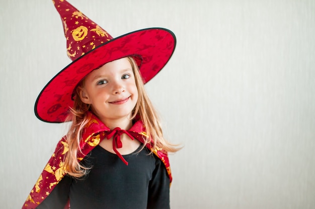 Little cheerful girl plays and has fun in a carnival witch costume