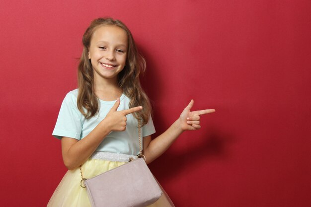 Little cheerful smiling girl in fashionable clothes on a colored background