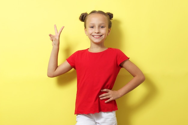 Little cheerful smiling girl in fashionable clothes on a colored background