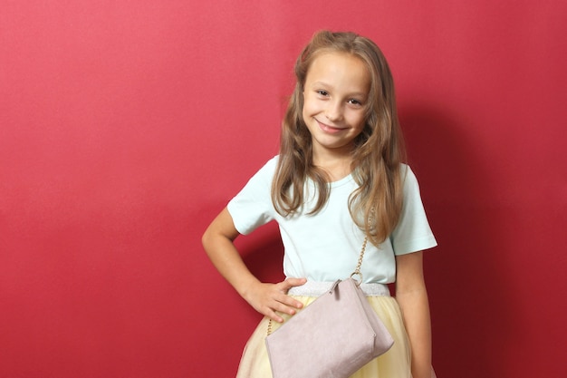 Little cheerful smiling girl in fashionable clothes on a colored background