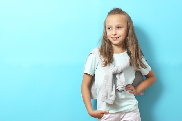 Little cheerful smiling girl in fashionable clothes on a colored background