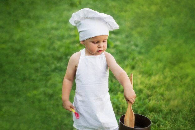 Little chef cooks on a picnic outdoors