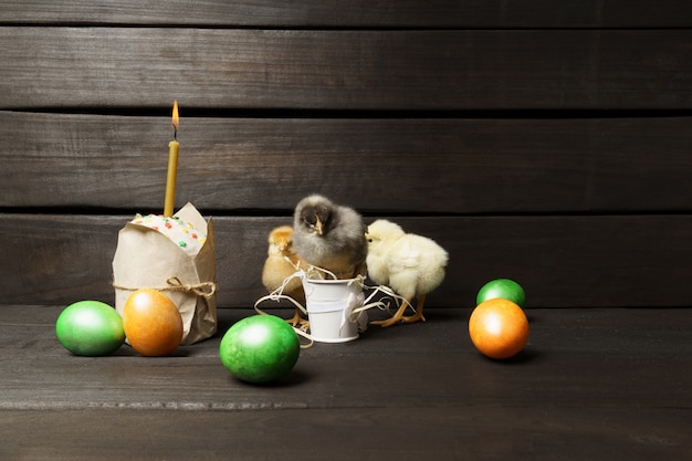 Little chicks Easter cake and colored eggs on a dark wooden table