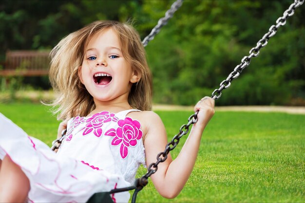 Little child blond girl having fun on a swing