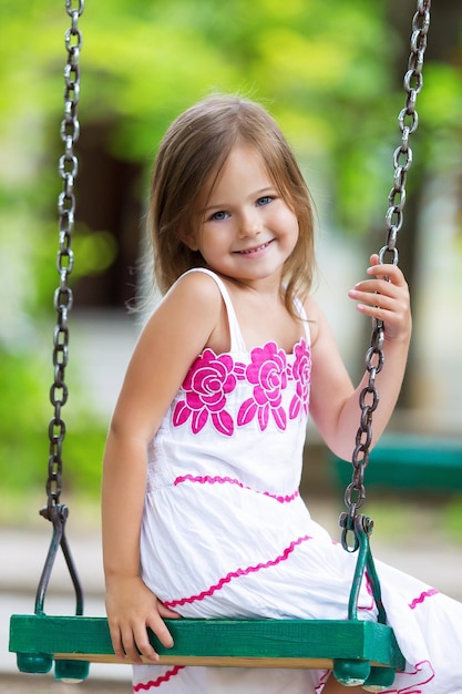 Little child blond girl having fun on a swing