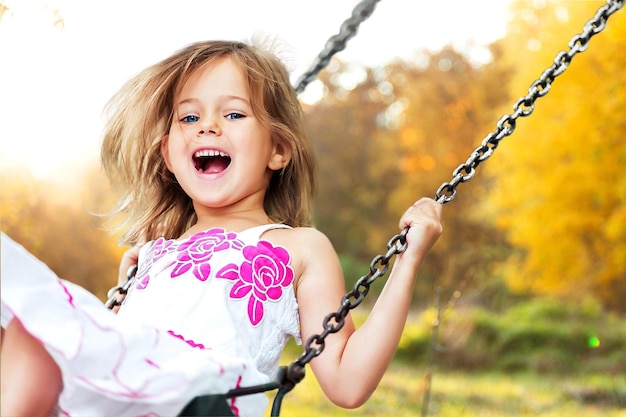 Little child blond girl having fun on a swing