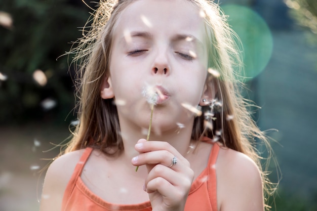 Little child blowing dandelion in sunny summer day