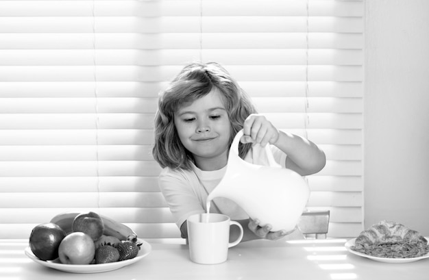 Little child boy having healthy breakfast Cute child pouring whole cows milk Kids nutrition and development Eating vegetables by child make them healthier