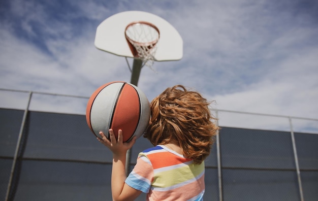 Ragazzino che gioca a basket con la scuola per bambini di basket ball basket