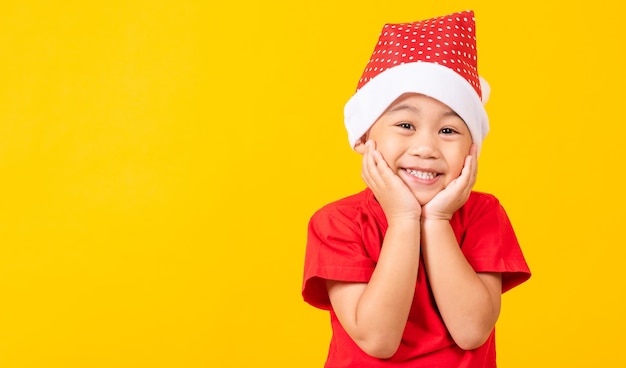 Little child boy smile and excited kids in santa claus hat shocked and surprised hand hold face