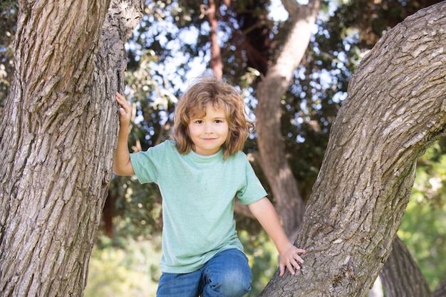 Little child boy trying to climb a tree Kids climbing a tree Kid boy playing and climbing a tree and hanging branch Happy boy enjoying summer day in a garden