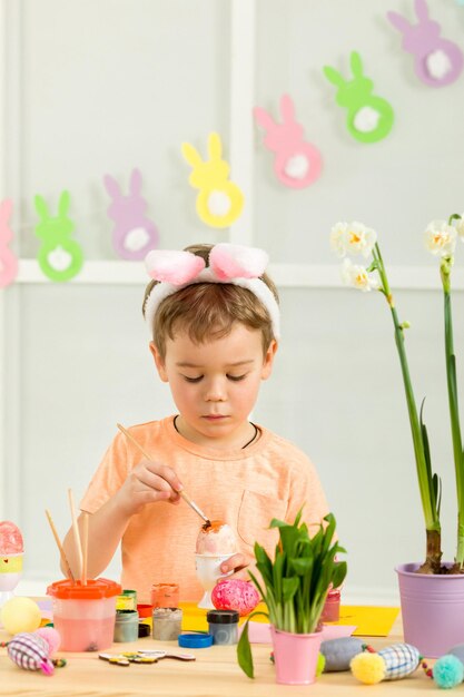 Little child boy with Easter bunny ears painting Easter eggs