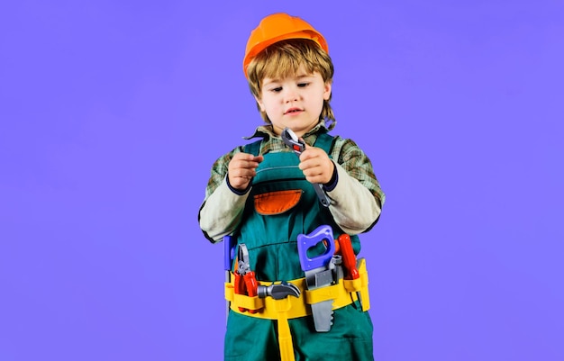 Little child in builder uniform and construction helmet with wrench kid boy with toolbelt little kid