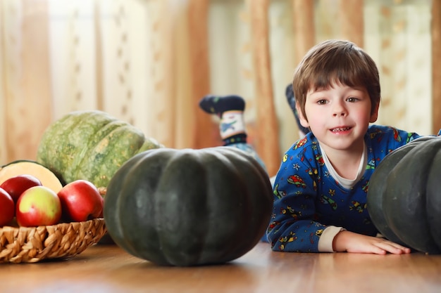 Little child choose a pumpkin at autumn. Child sitting on giant pumpkin. Pumpkin is traditional vegetable used on American holidays - Halloween and Thanksgiving Day.