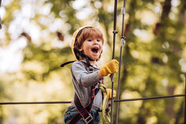 Little child climbing in adventure activity park with helmet and safety equipment Toddler climbing i