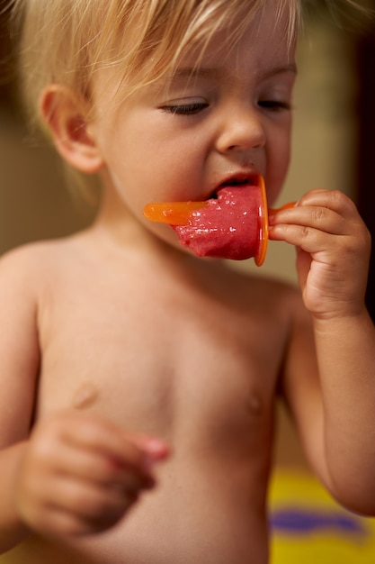 Il piccolo bambino mangia il gelato su un ritratto del bastone