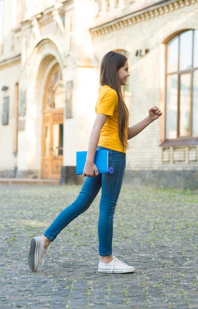 Little child girl back to school hold textbook, towards knowledge concept.