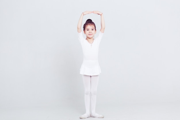 Little child girl dance ballet at white background Portrait of small ballerina smiling