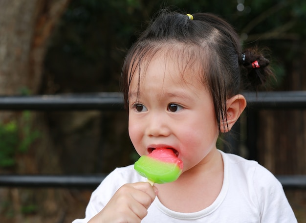 小さな子供の女の子は公園でアイスクリームを食べる