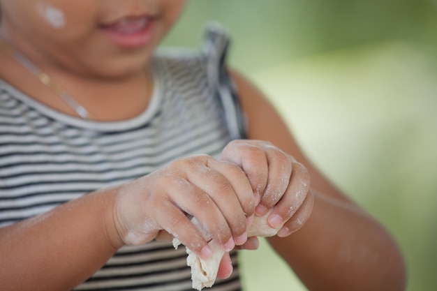 小さな子供の女の子の手は生地を混練