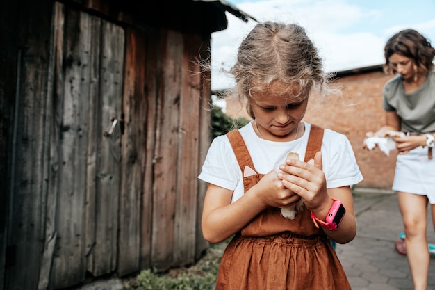 Little child girl is holding the chicken on the farm. Portrait of little girl with chicken