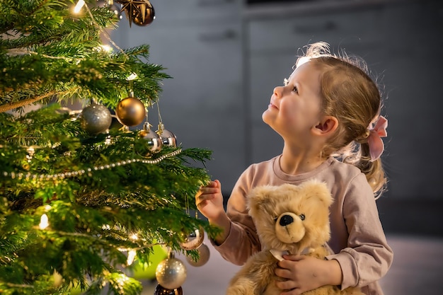 Little child girl playing with teddy bear in christmas time pretty kid in decorated new year home wi