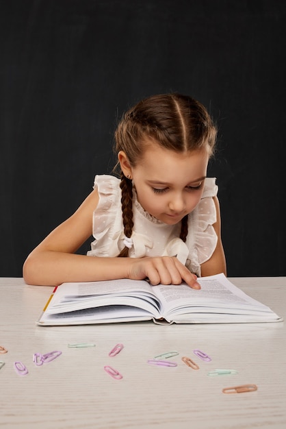 Little child girl reading a book in the classroom