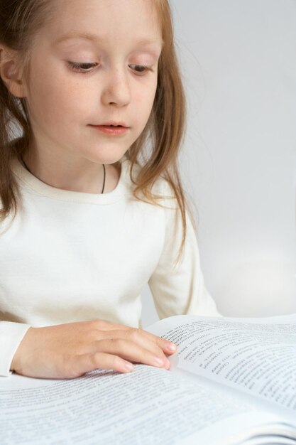 Photo little child girl reading a book. close-up portrait