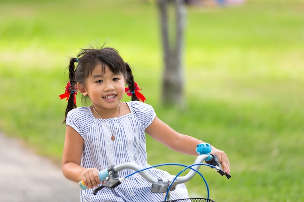 Little child girl riding bike in park