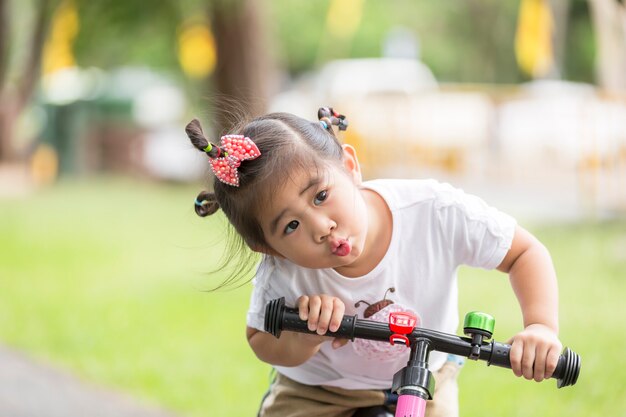 Little child girl riding bike in park