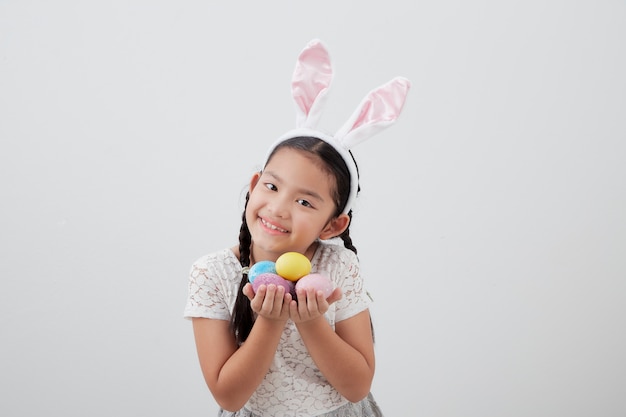 Little child girl with easter bunny ears holding egg