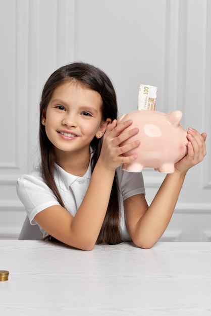 Little child girl with piggy bank at home