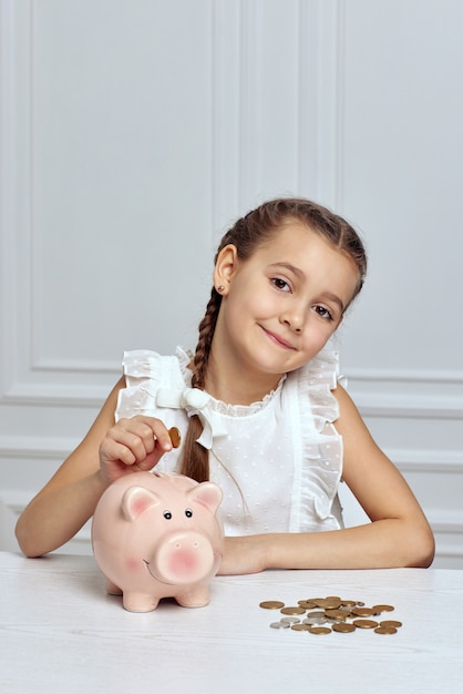 Little child girl with piggy bank at home