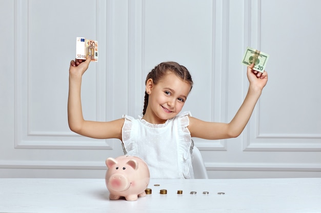 Photo little child girl with piggy bank at home